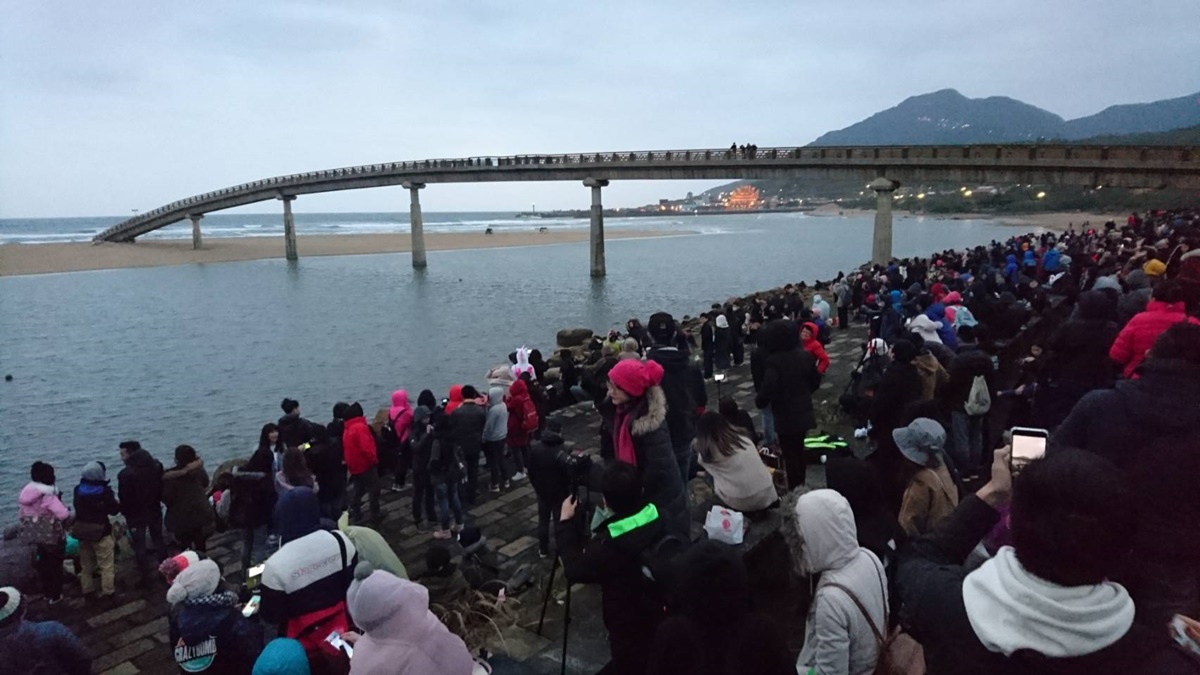 2018 Fulong Yingguang 관광객들은 Rainbow Bridge 옆에서 새벽을 기다립니다.